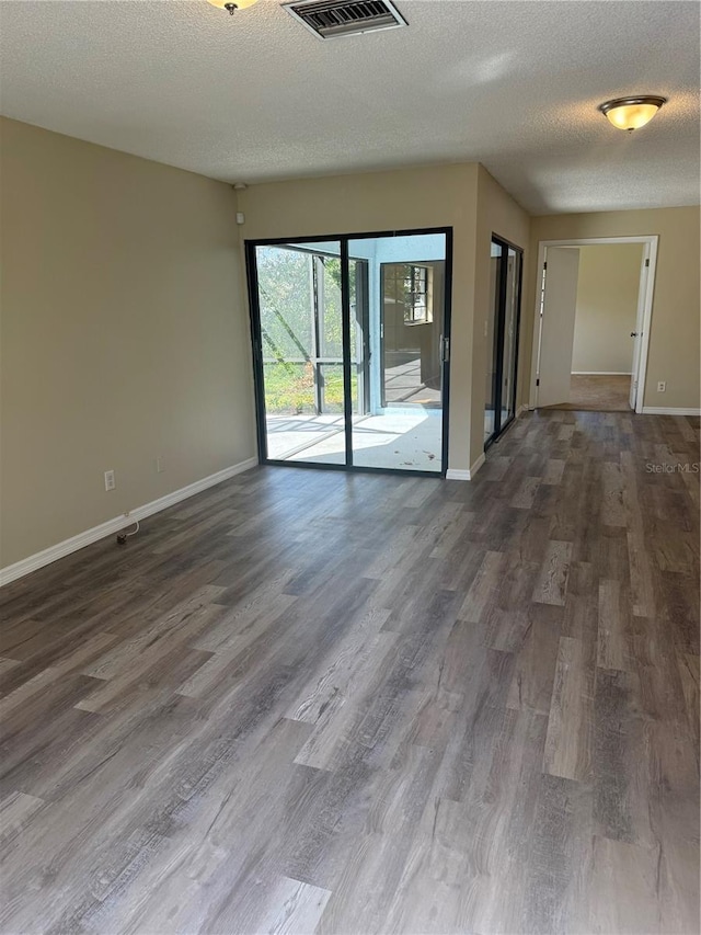 empty room with visible vents, baseboards, and dark wood-style floors