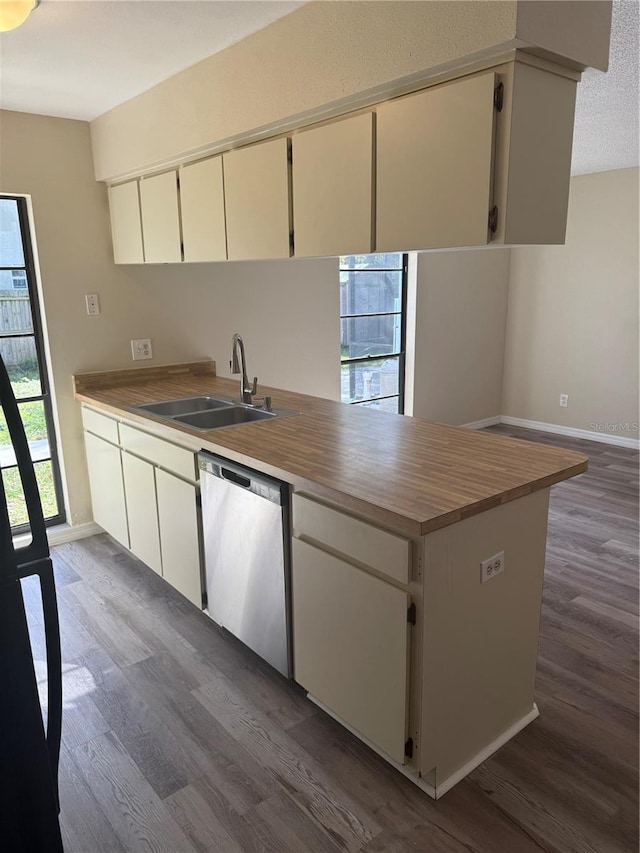 kitchen with a sink, stainless steel dishwasher, dark wood-style floors, butcher block counters, and baseboards