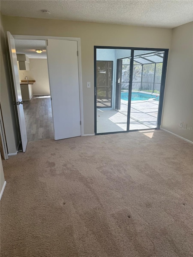 spare room with carpet flooring, a textured ceiling, and baseboards