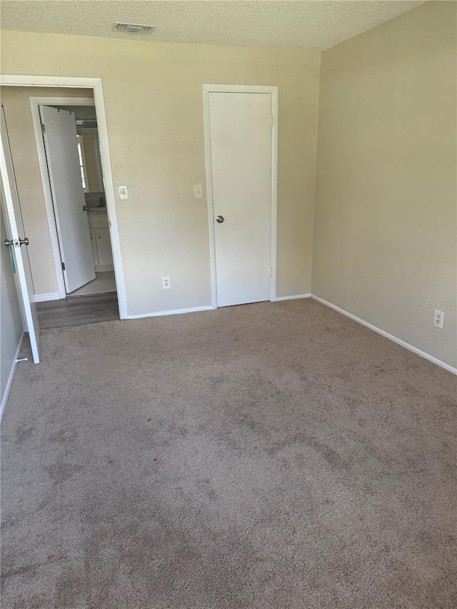 unfurnished bedroom featuring baseboards, carpet, visible vents, and a textured ceiling