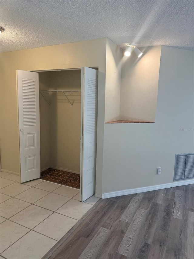 unfurnished bedroom with a textured ceiling, visible vents, a closet, and light wood-type flooring