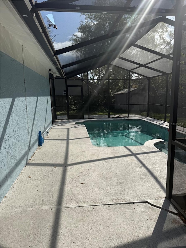 view of swimming pool featuring glass enclosure, a fenced in pool, and a patio area