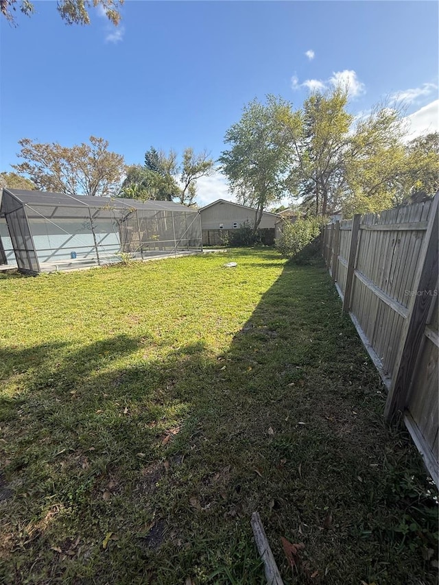 view of yard with glass enclosure and a fenced backyard