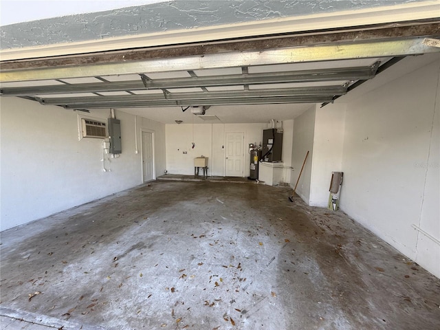 garage with electric water heater, a wall unit AC, electric panel, a garage door opener, and a sink