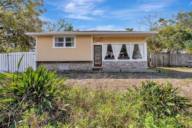 view of front of house with stone siding and fence