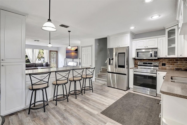 4716 Gazania St, New Port Richey, FL 34652 - kitchen featuring visible vents, dark countertops, stainless steel appliances, a kitchen bar, and white cabinetry