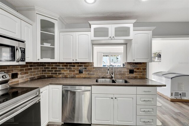 4716 Gazania St, New Port Richey, FL 34652 - kitchen featuring stainless steel appliances, dark countertops, decorative backsplash, white cabinetry, and a sink