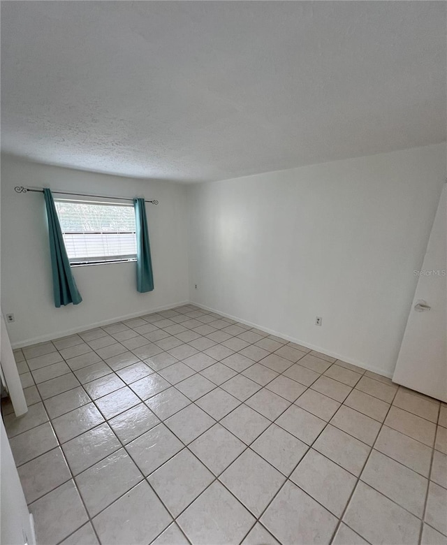 unfurnished room with a textured ceiling and baseboards