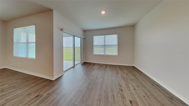 spare room with baseboards and light wood finished floors