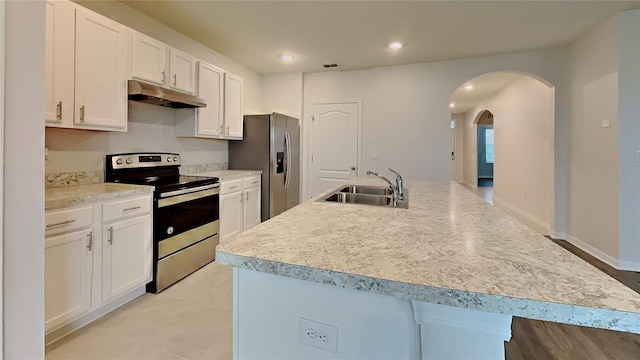 kitchen with white cabinets, an island with sink, stainless steel appliances, light countertops, and a sink