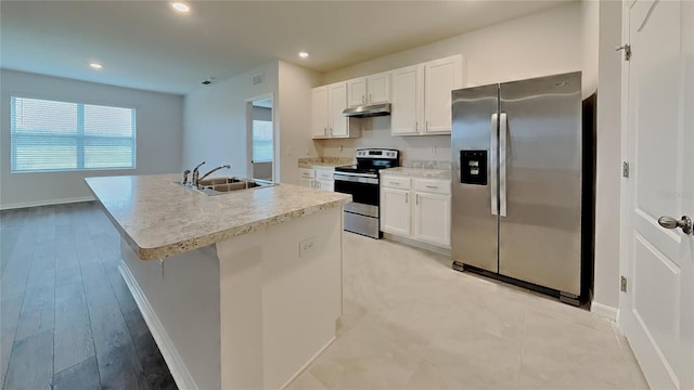 kitchen featuring appliances with stainless steel finishes, an island with sink, a sink, and white cabinetry