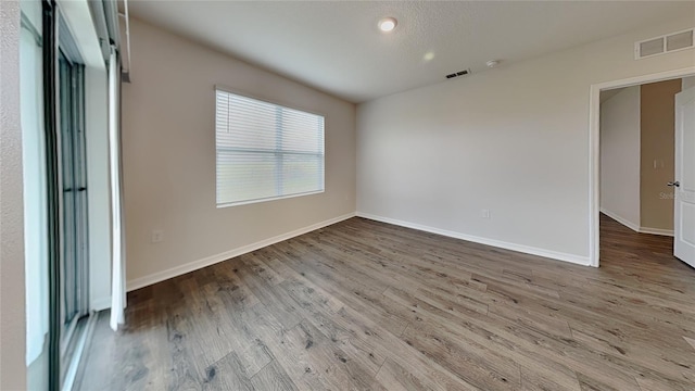 spare room featuring visible vents, baseboards, and wood finished floors