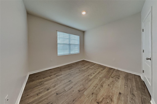 unfurnished bedroom featuring a textured ceiling, wood finished floors, and baseboards