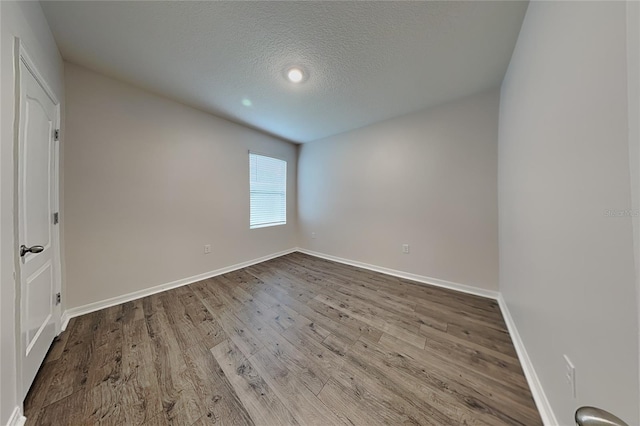 unfurnished bedroom featuring a textured ceiling, wood finished floors, and baseboards