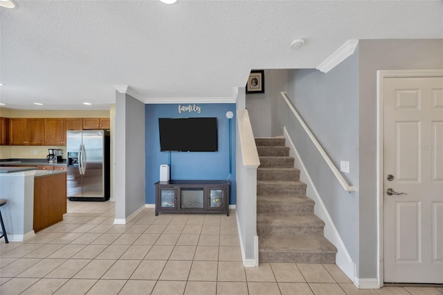 stairs with a textured ceiling, ornamental molding, tile patterned flooring, and baseboards