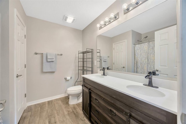 full bath with wood finished floors, a sink, toilet, and baseboards