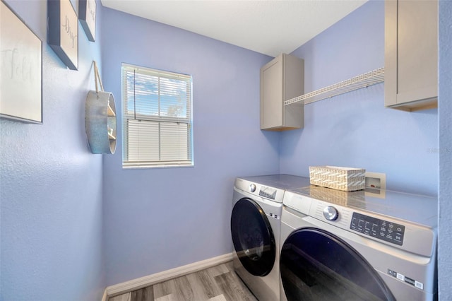 laundry room with cabinet space, baseboards, separate washer and dryer, and light wood-style floors