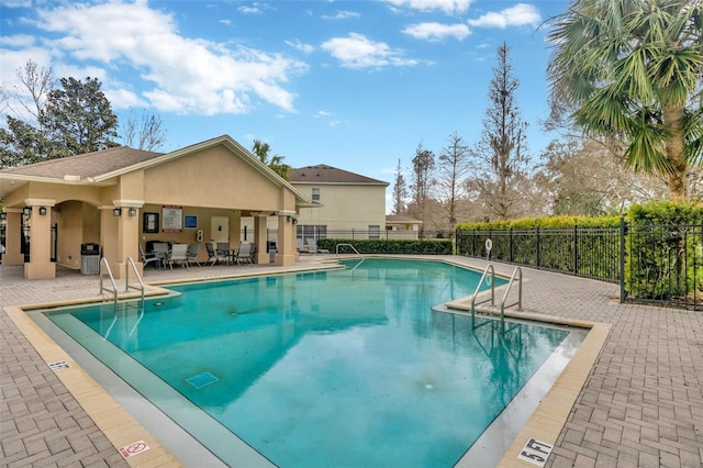 community pool with a patio area and fence