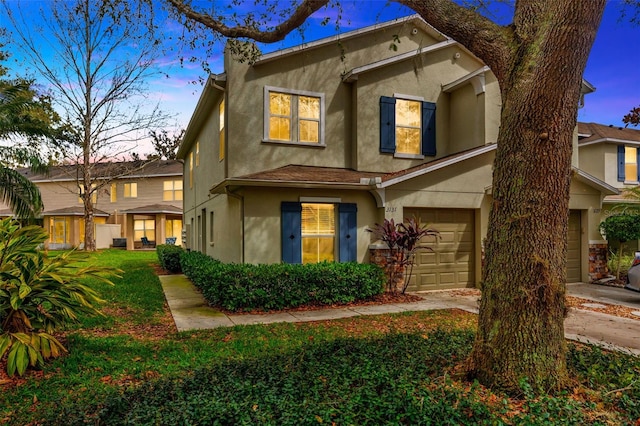 view of front facade with a garage, a yard, driveway, and stucco siding