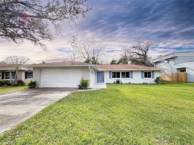 ranch-style home with concrete driveway, an attached garage, fence, a yard, and stucco siding