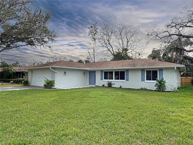 ranch-style house featuring an attached garage, driveway, a front lawn, and stucco siding