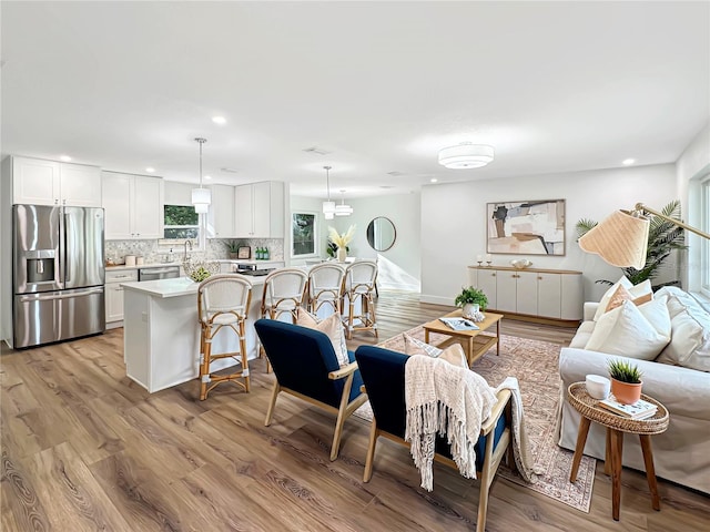 living area featuring baseboards, recessed lighting, and light wood-style floors