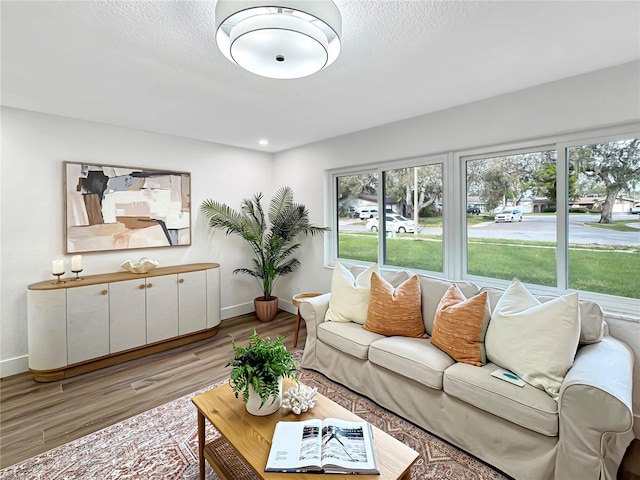 living room with light wood-style floors, recessed lighting, a textured ceiling, and baseboards