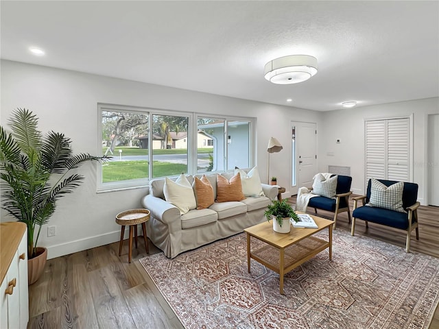 living area with baseboards, wood finished floors, and recessed lighting