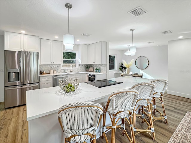 kitchen with decorative backsplash, visible vents, stainless steel appliances, and a sink