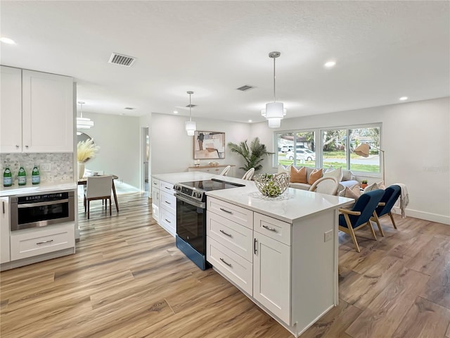 kitchen with appliances with stainless steel finishes, visible vents, light wood finished floors, and white cabinetry