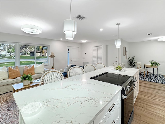 kitchen featuring light wood-style flooring, black range with electric cooktop, visible vents, and white cabinets