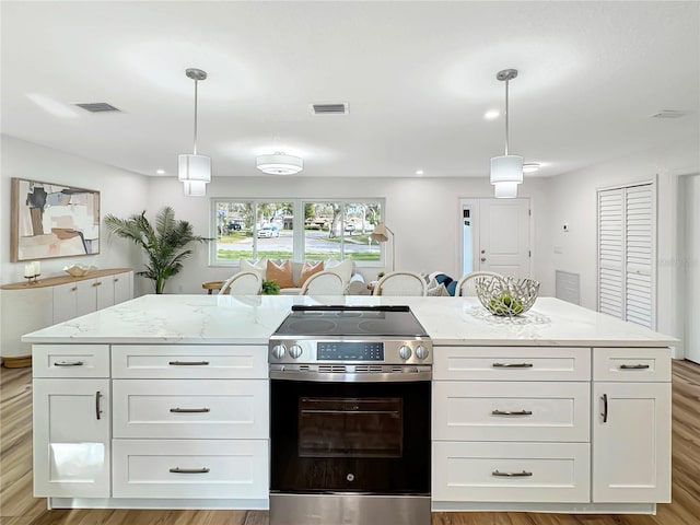 kitchen featuring light stone countertops, white cabinetry, visible vents, and stainless steel range with electric cooktop