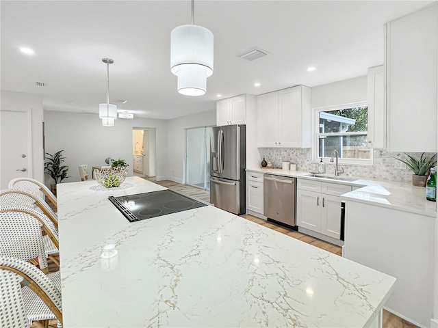 kitchen featuring a sink, visible vents, white cabinets, appliances with stainless steel finishes, and tasteful backsplash