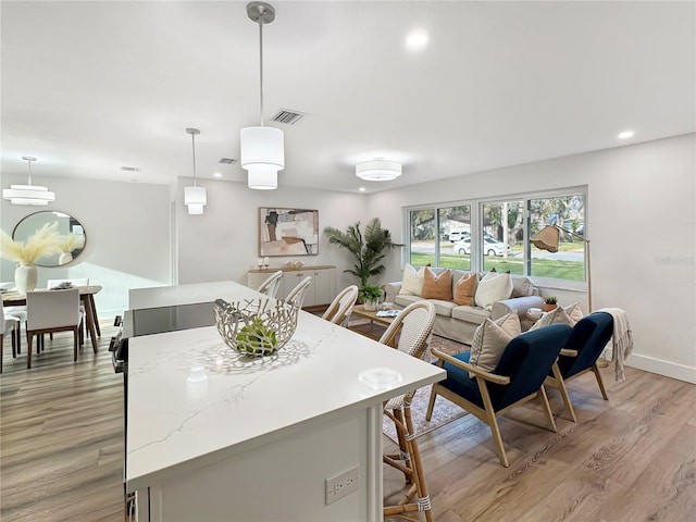 kitchen with light wood finished floors, visible vents, baseboards, a center island, and recessed lighting