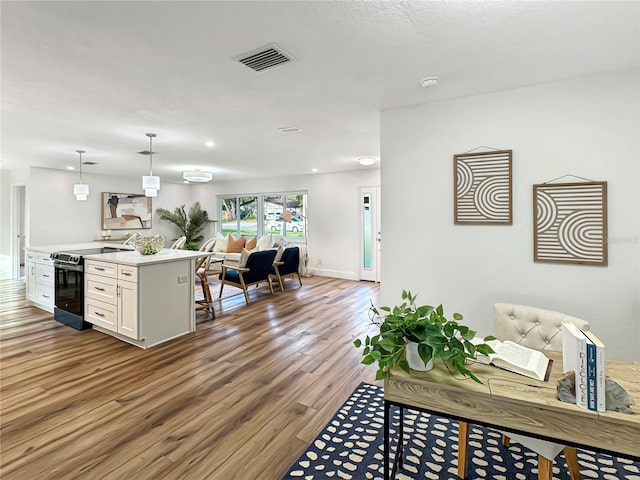 kitchen with range with electric cooktop, wood finished floors, visible vents, white cabinets, and open floor plan