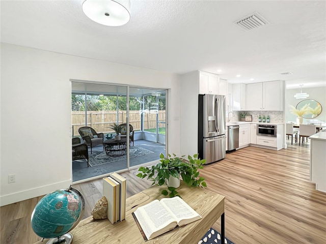 living area featuring light wood-type flooring, baseboards, and visible vents