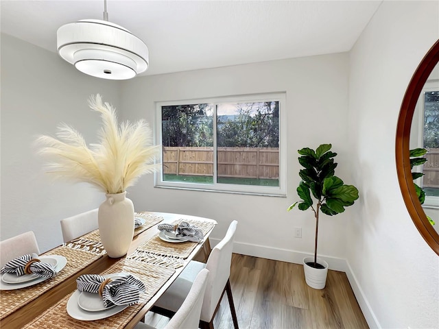 dining space with baseboards and wood finished floors