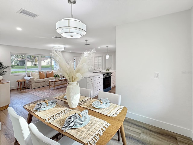 dining room featuring wood finished floors, visible vents, and baseboards