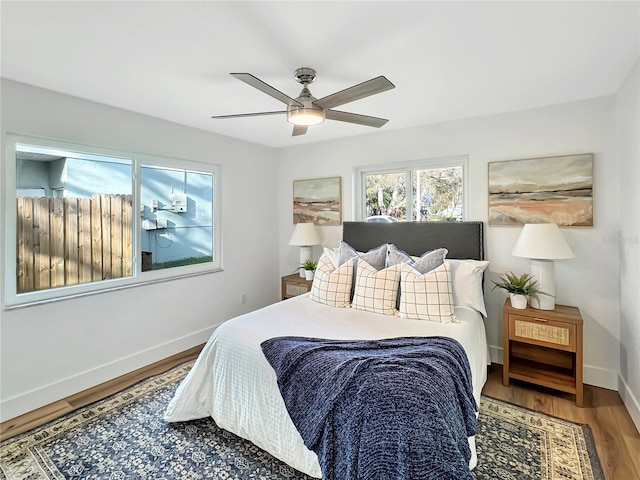 bedroom with ceiling fan, baseboards, and wood finished floors