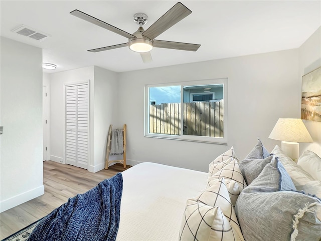 bedroom featuring a closet, visible vents, light wood-style floors, a ceiling fan, and baseboards