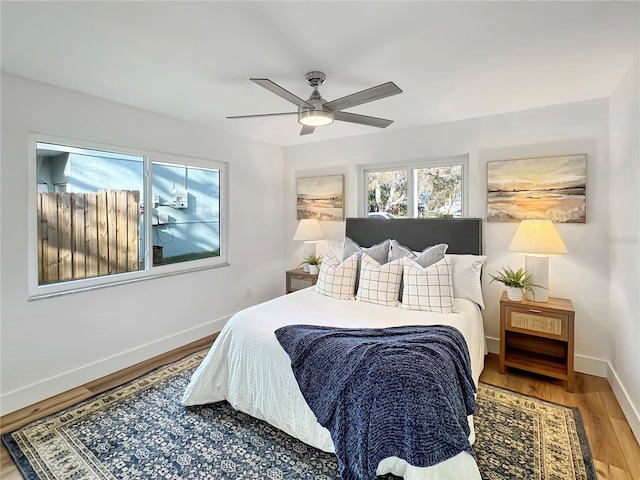 bedroom with ceiling fan, wood finished floors, and baseboards