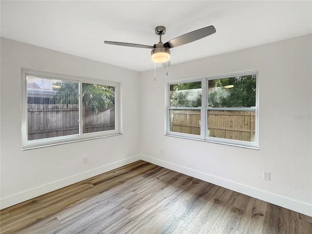 unfurnished room featuring a healthy amount of sunlight, baseboards, and wood finished floors