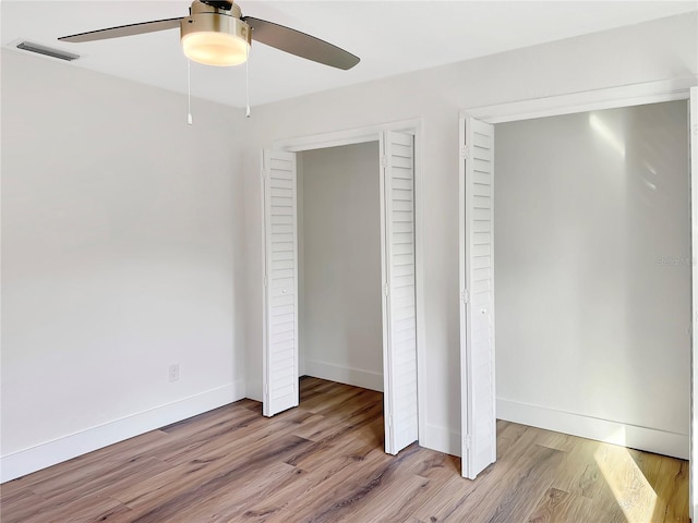 unfurnished bedroom with ceiling fan, light wood-style flooring, visible vents, and baseboards