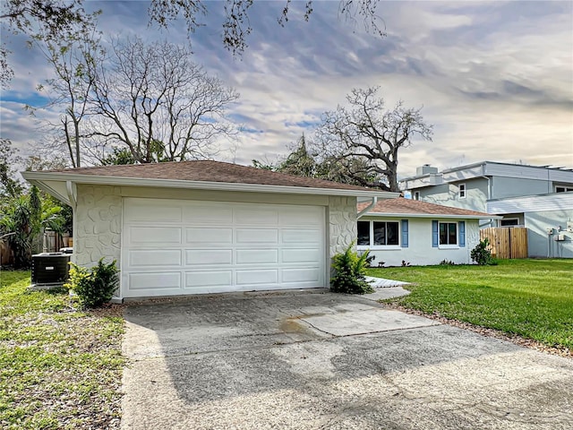 ranch-style home with an attached garage, cooling unit, fence, driveway, and a front yard