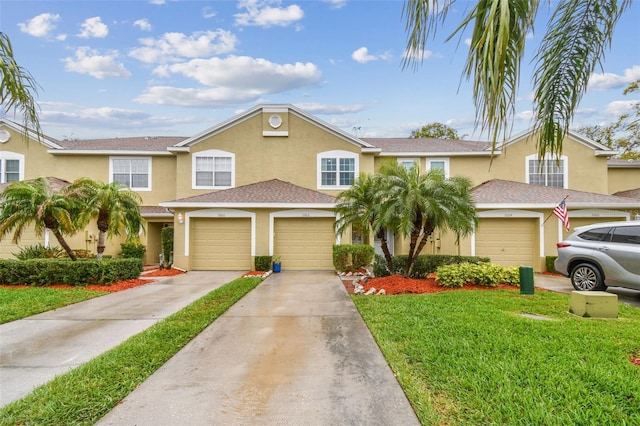 multi unit property with concrete driveway, a front lawn, and stucco siding