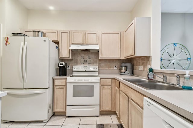 kitchen with white appliances, light countertops, light brown cabinetry, under cabinet range hood, and a sink