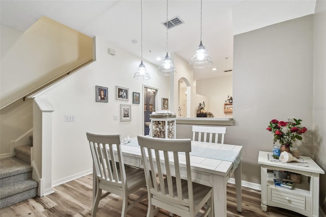 dining room featuring visible vents, stairs, arched walkways, and wood finished floors