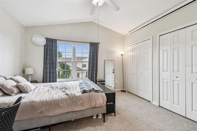 carpeted bedroom featuring multiple closets, vaulted ceiling, baseboards, and ceiling fan