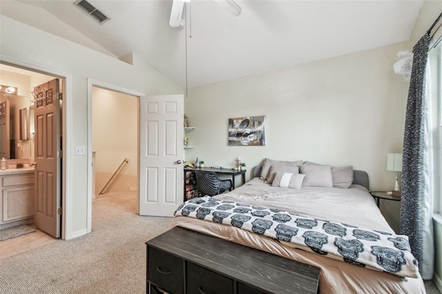 bedroom with visible vents, light colored carpet, lofted ceiling, ensuite bathroom, and a sink