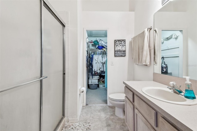 bathroom with toilet, a shower stall, a walk in closet, and vanity